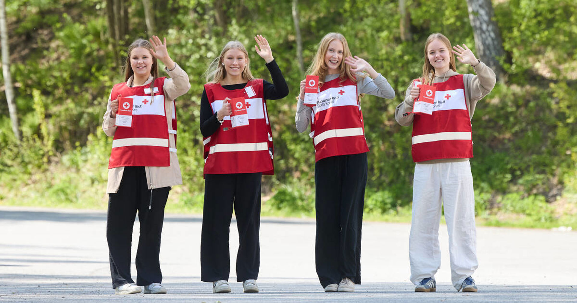 Nuoret vapaaehtoiset vilkuttavat kohti kameraa.