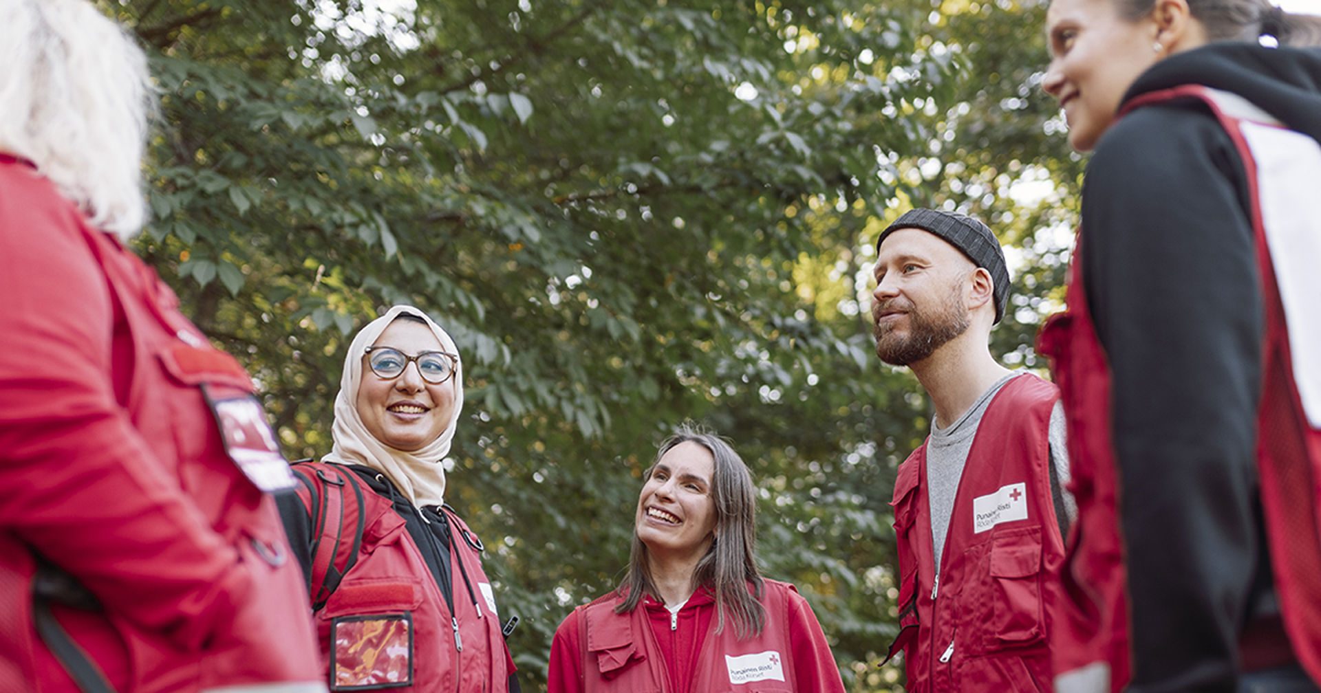 Suomen Punaisen Ristin vapaaehtoiset juttelevat ringissä puistossa.