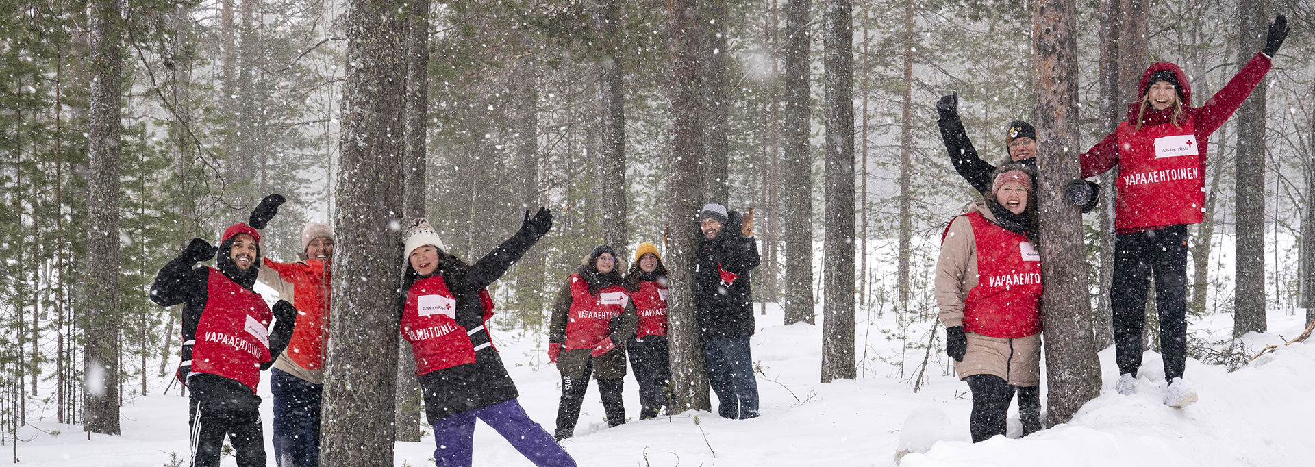 Joukko vapaaehtoisia vilkuttaa kameralle lumisessa maastossa.