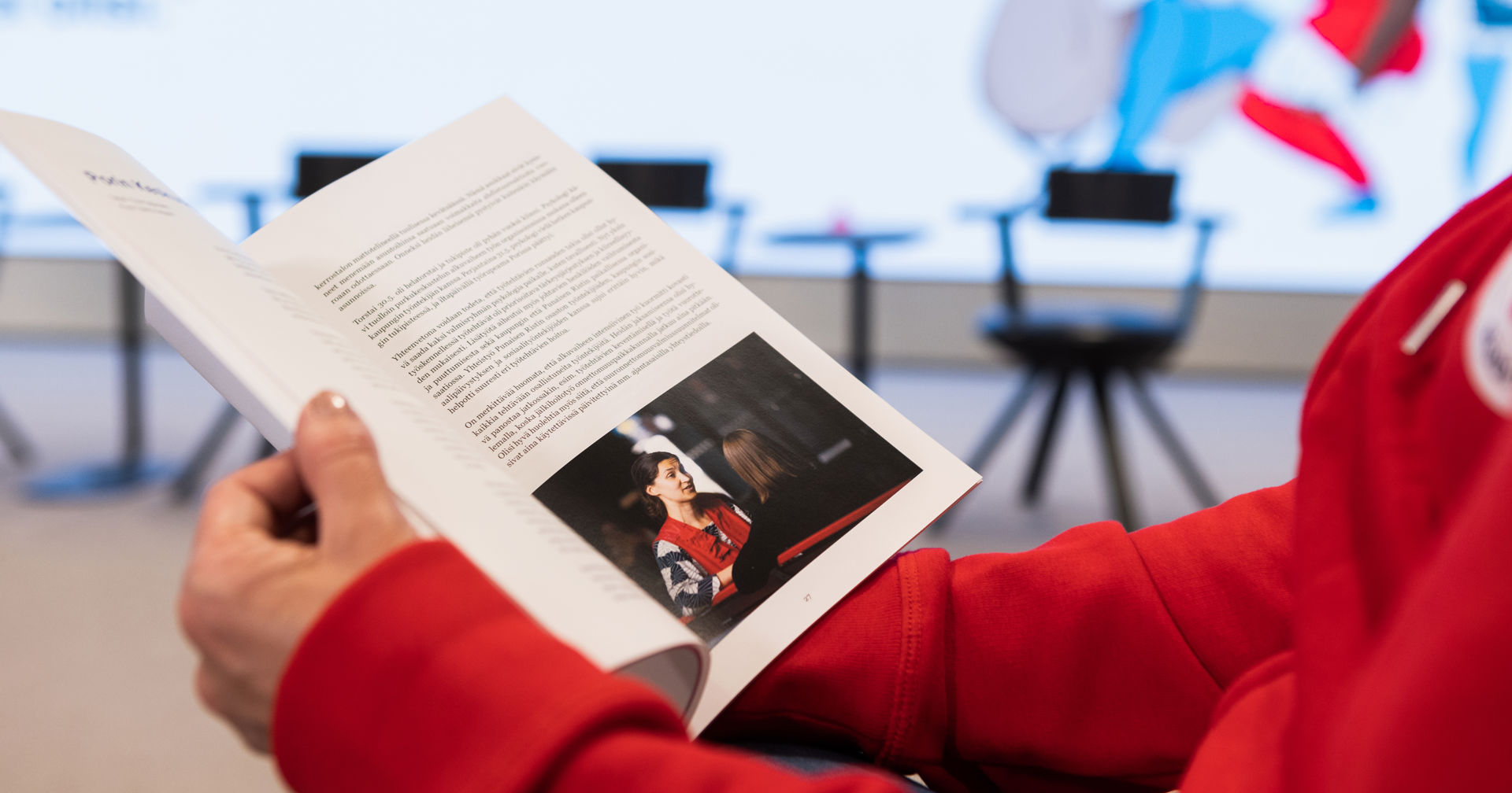 Kädet pitelevät Punaisen Ristin esitettä.