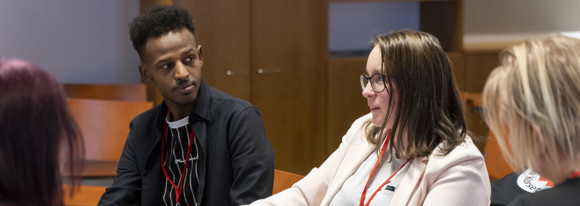 Neljä henkilöä istuu pöydän ääressä ja keskustelee.