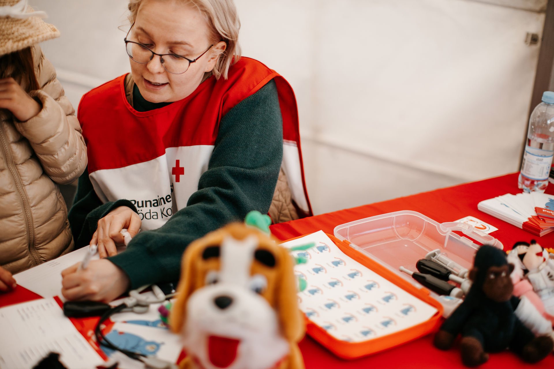 Vapaaehtoinen kirjoittaa jotain nallesairaalan pöydällä.