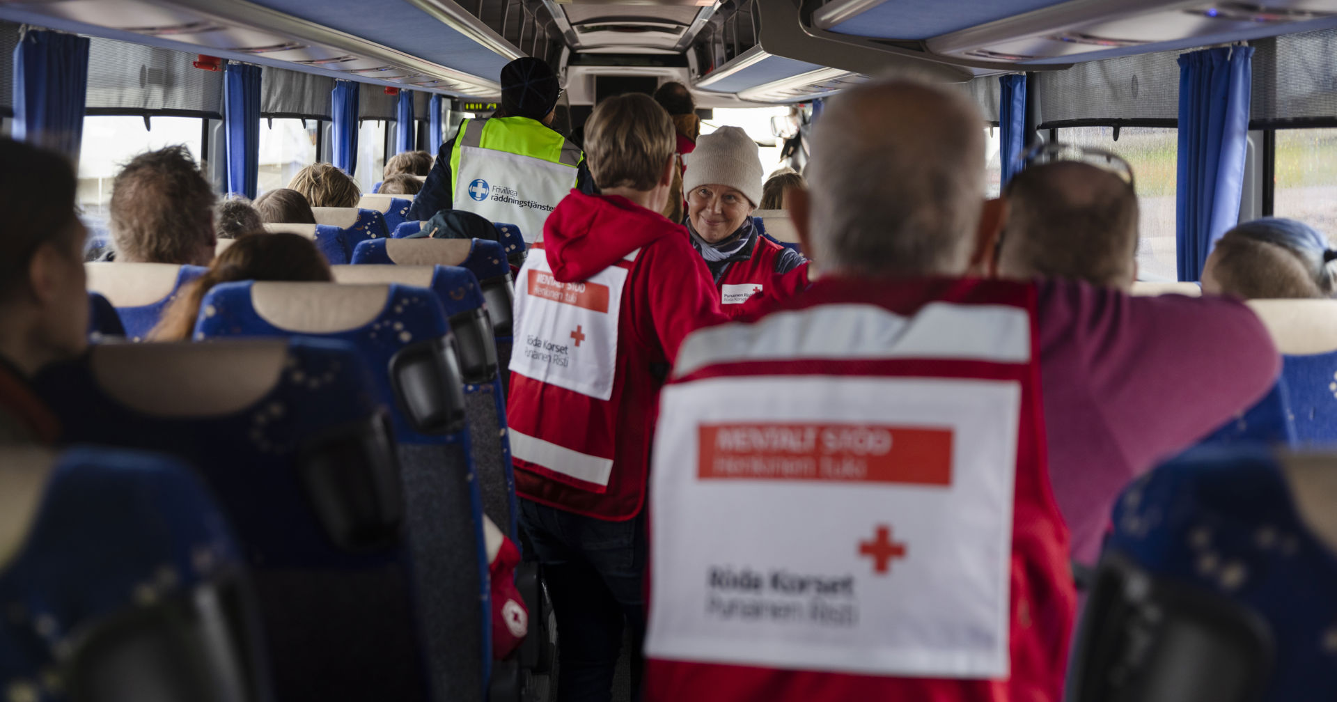 Punaisen Ristin vapaaehtoisia bussissa vapaaehtoisliiveissään.