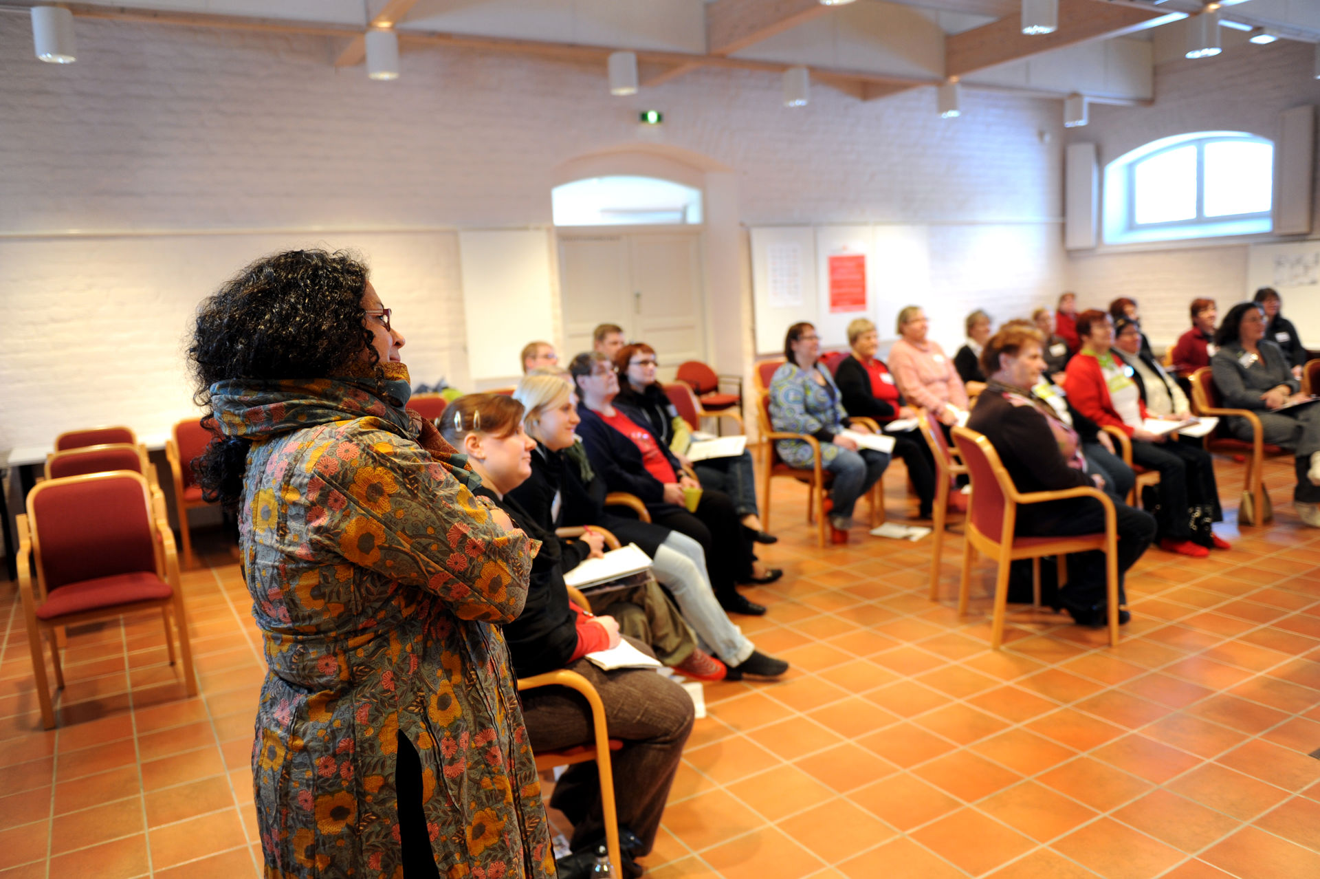 Ihmiset istuvat luokkahuoneessa puoliympyrässä.