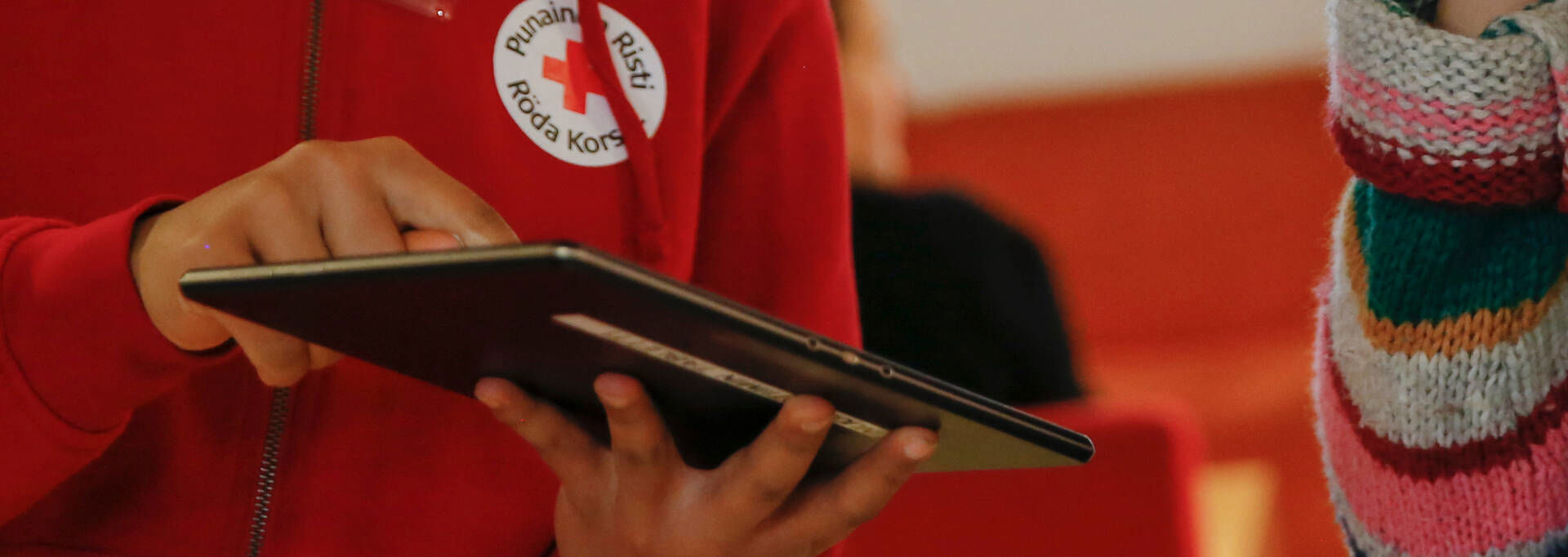 Henkilön käsissä on tablettitietokone, jota hän esittelee toiselle.