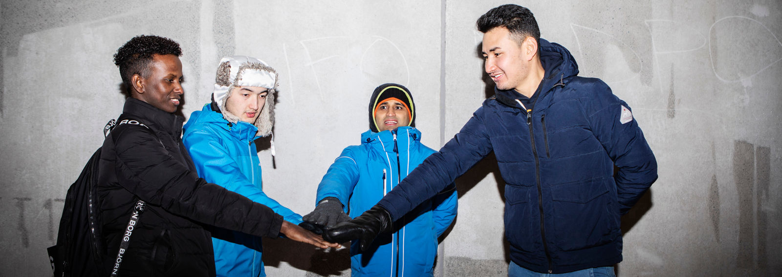 Neljä nuorta on laittanut kädet yhteen piirin keskelle.