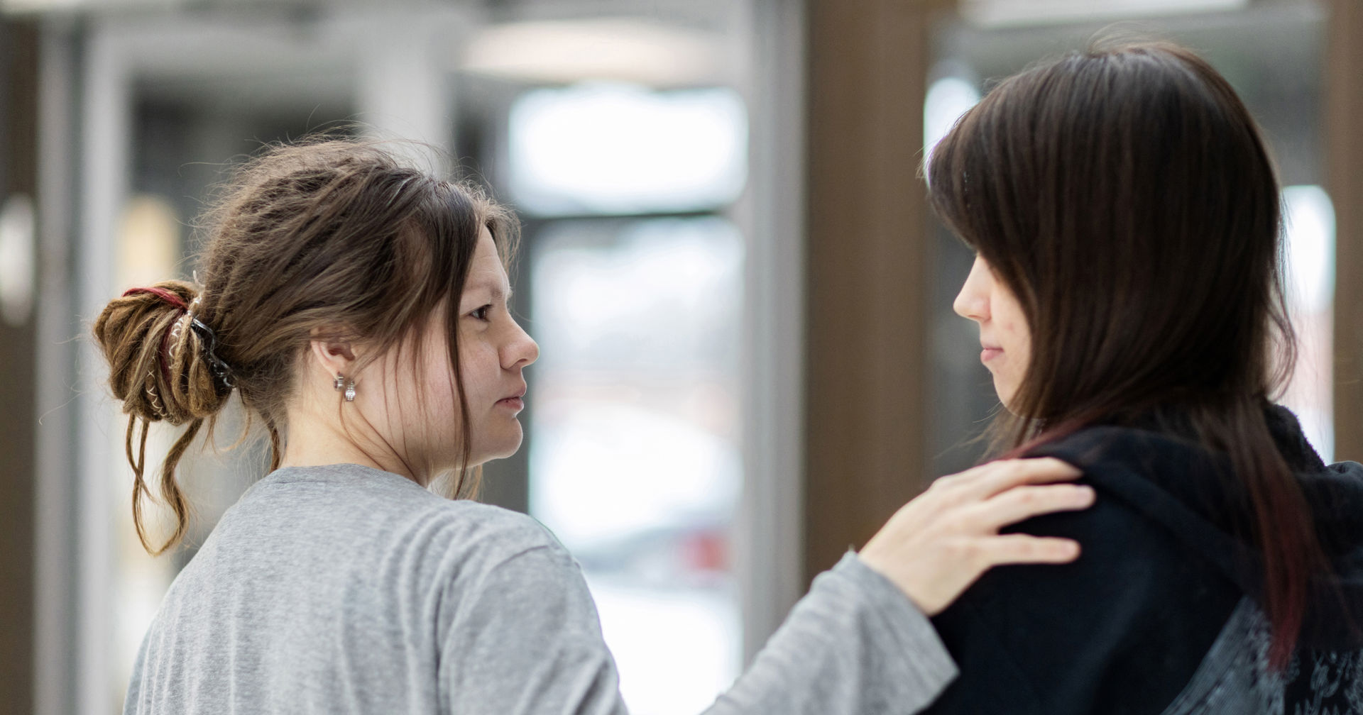 Kaksi henkilöä katsoo toisiaan. Yksi on laittanut käden toisen olalle.