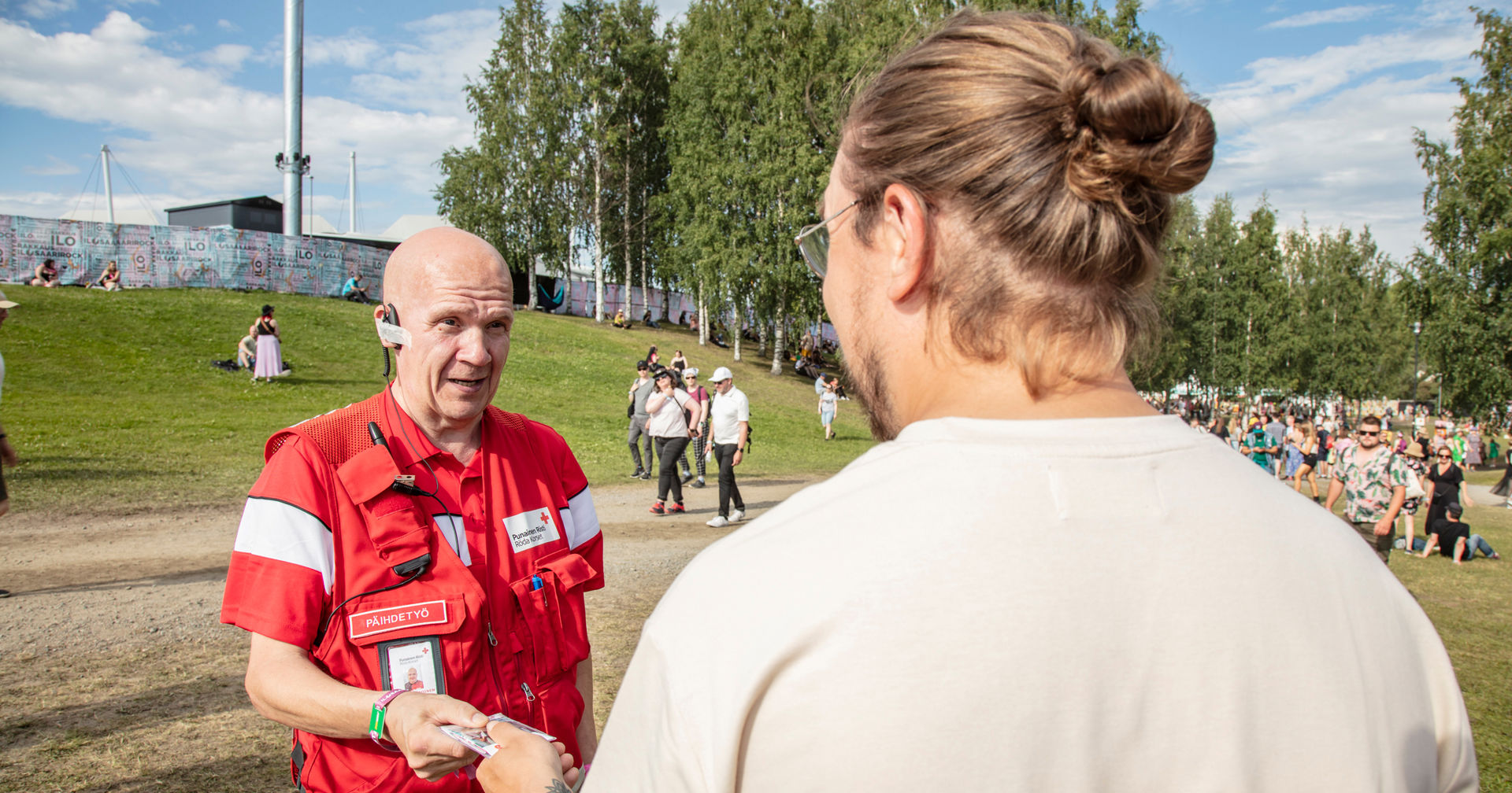 Päihdetyön vapaaehtoinen ojentaa esitettä festarien viettäjälle.