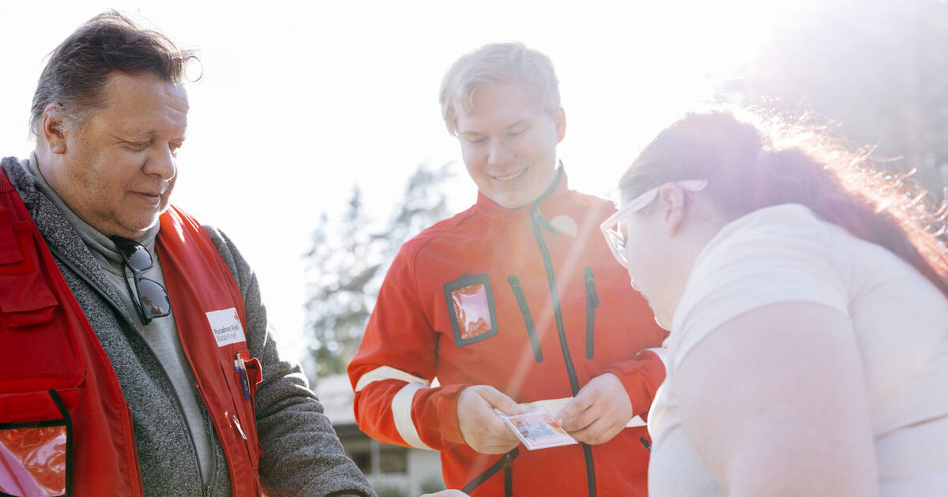 Kaksi Punaisen Ristin vapaaehtoista juttelee nuoren kanssa.