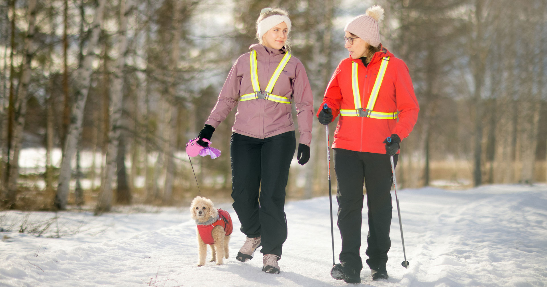 Kaksi lenkkeilijää talvisessa maisemassa. Lenkkeilijät katsovat toisiaan.