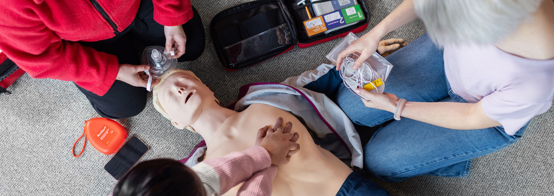 Kolme henkilöä harjoittelee ensiapua ensiapunukella.