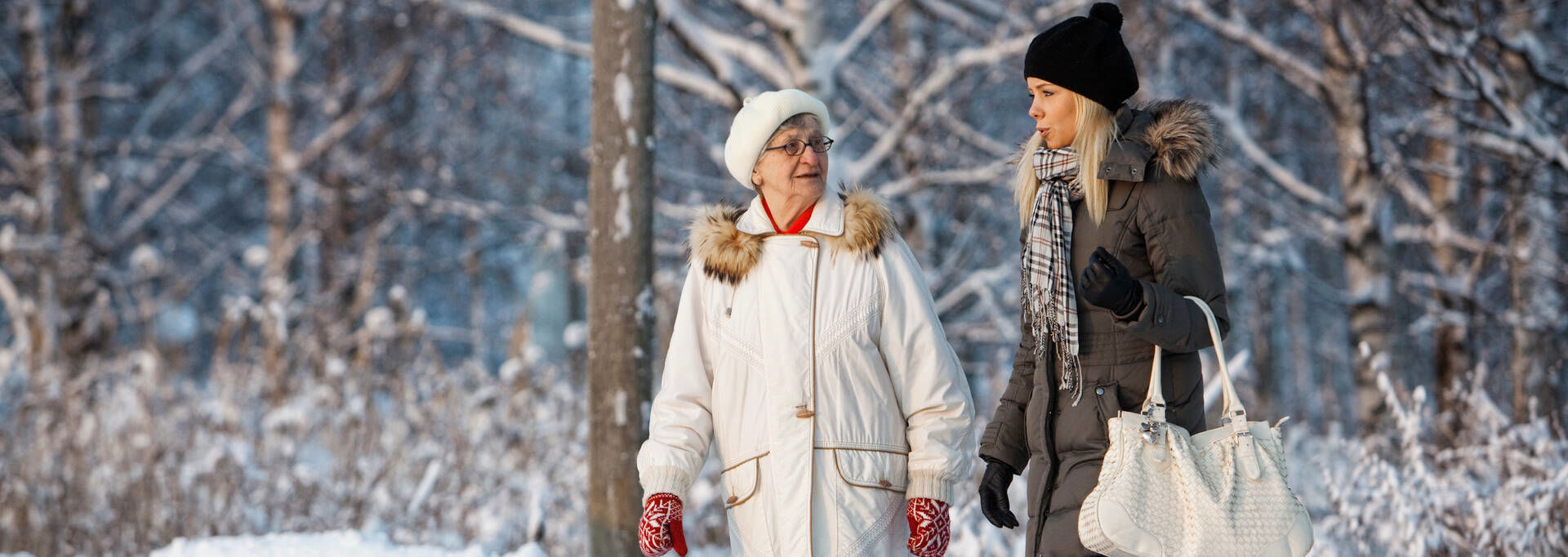Kaksi henkilöä kävelevät lumisissa maisemissa.