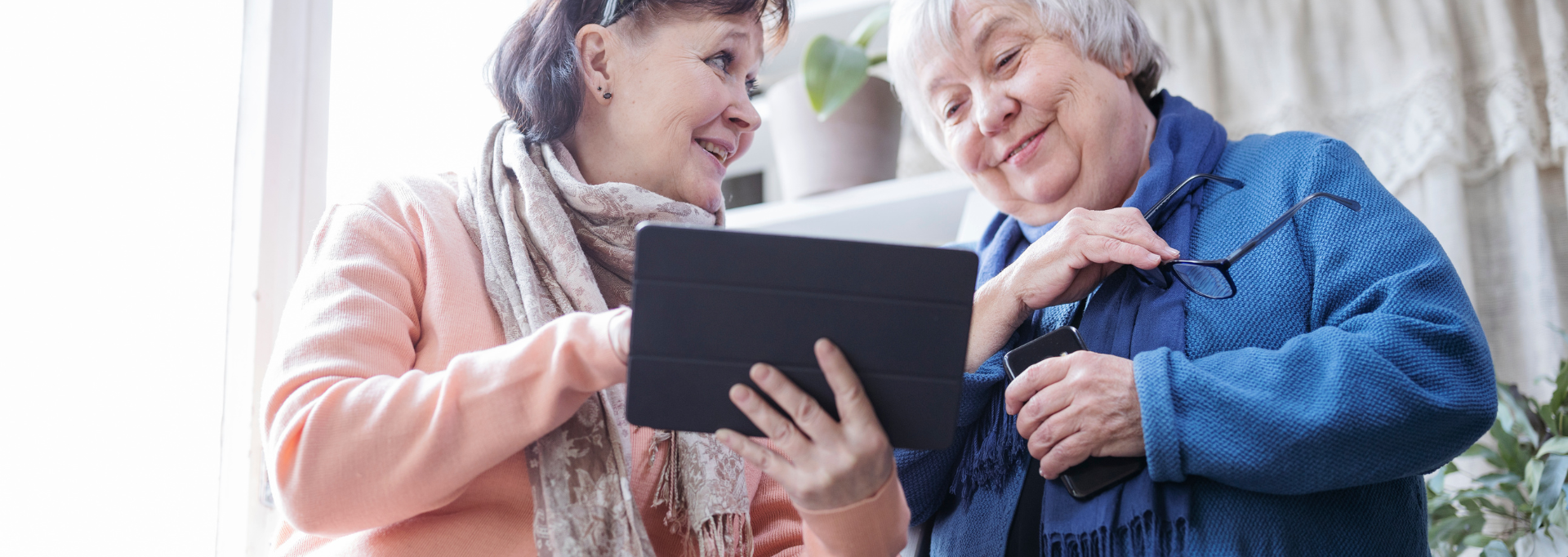 Kaksi hymyilevää henkilöä katsoo yhdessä tablettitietokonetta.