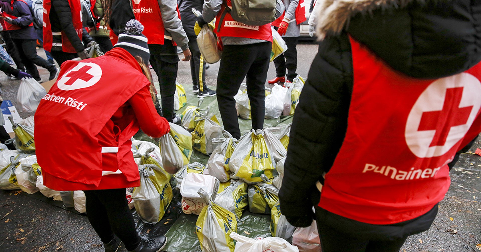 Vapaaehtoisia kauppakassien kanssa ulkona.