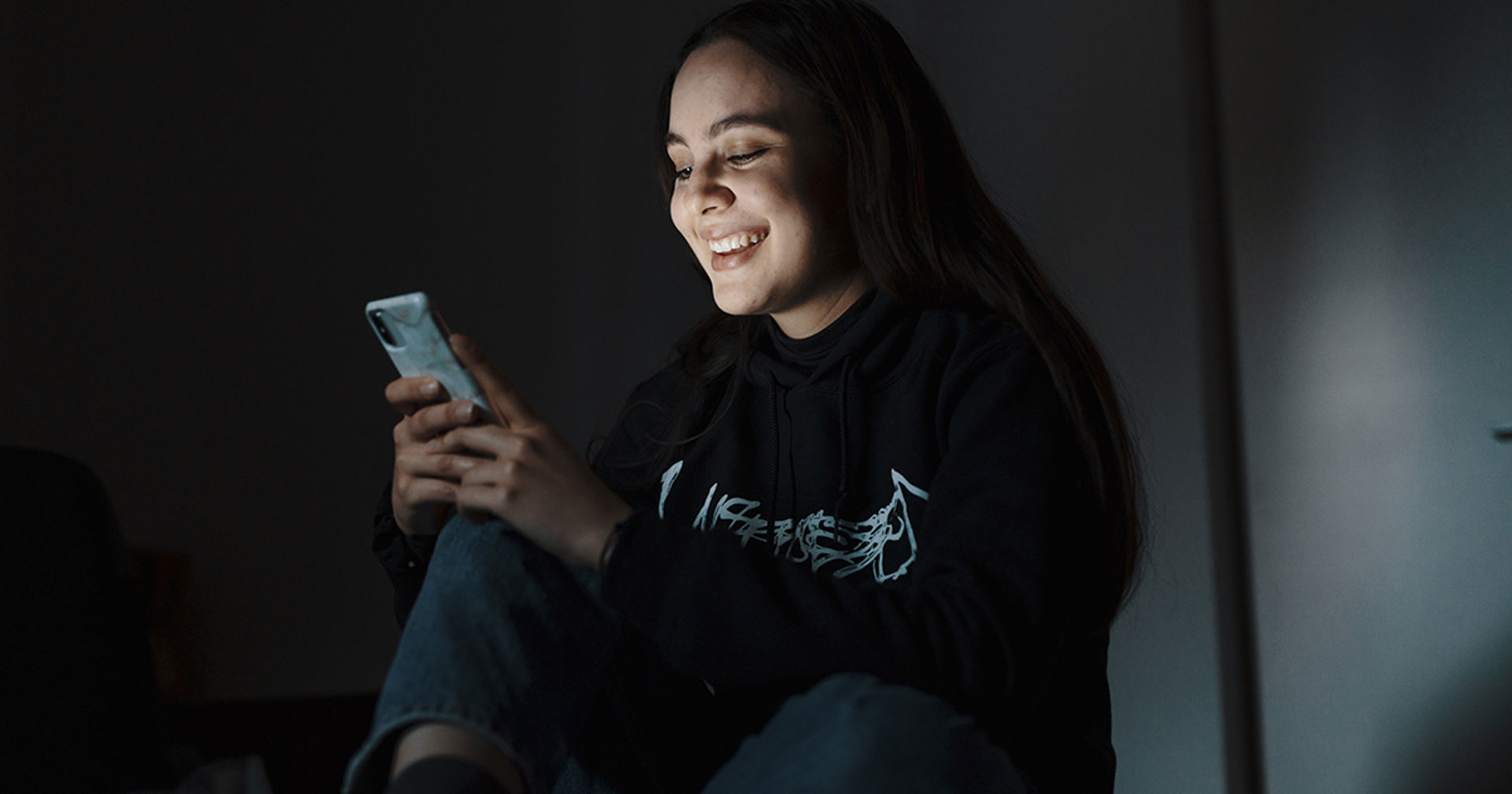 Nuori katsoo puhelintaan hymyillen.