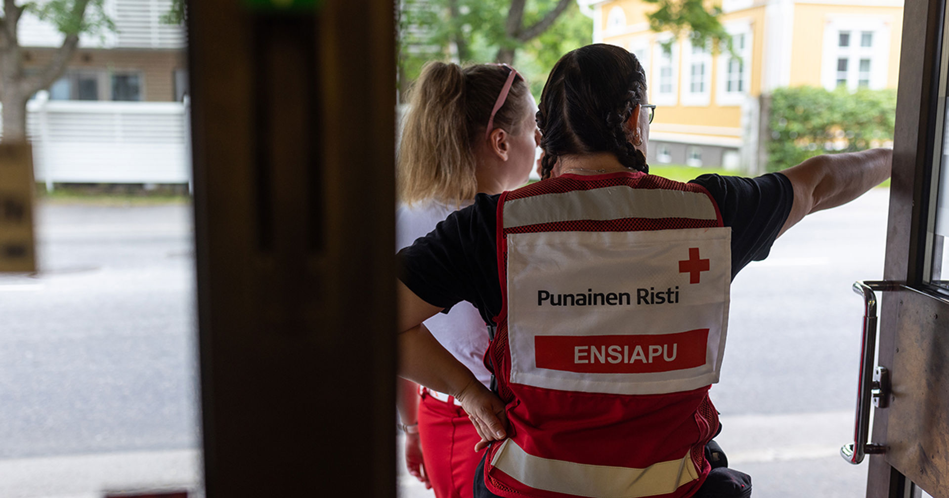 Kaksi punaisen ristin vapaaehtoista oven suussa.