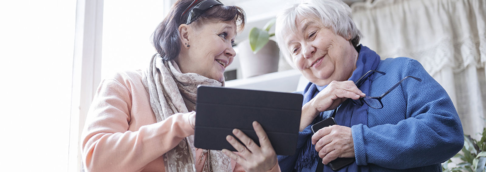 Kaksi henkilöä katsoo yhdessä tablettia ja hymyilevät toisilleen.