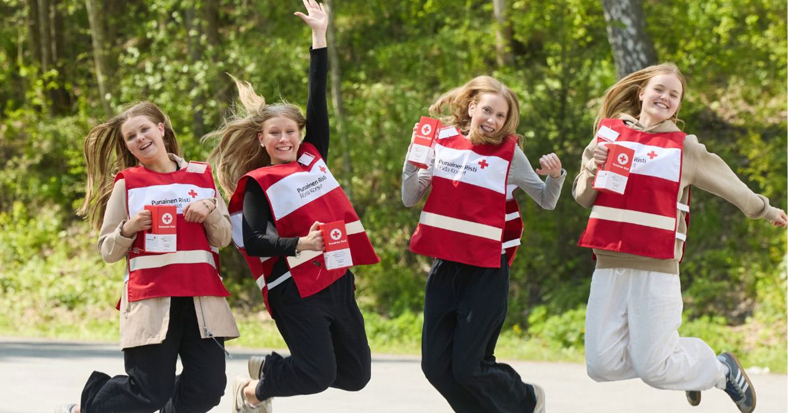 Kaksi nuorta Nälkäpäiväkeräys lippaat käsissään ja Punaisen Ristin liivit päällään.
