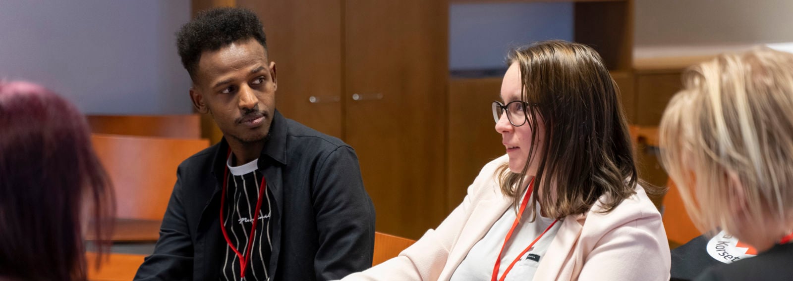 Neljä henkilöä istuu pöydän ääressä ja keskustelee.