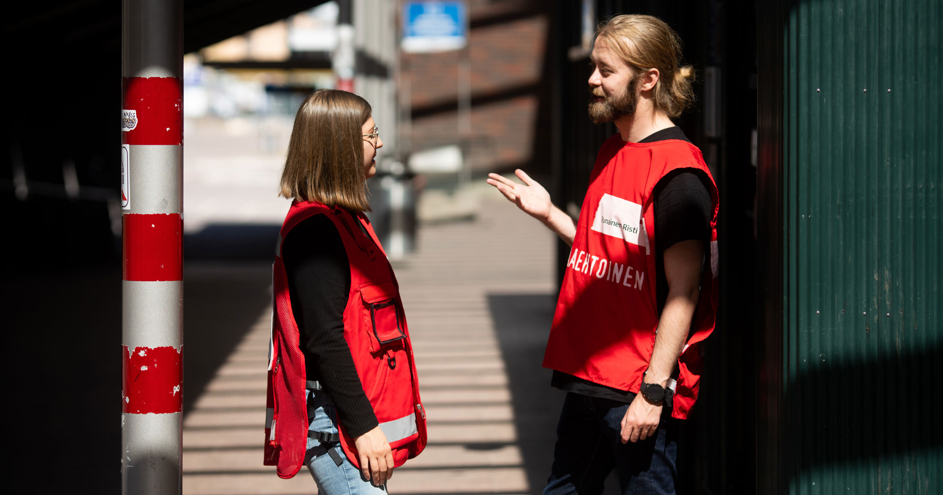 Kaksi Suomen Punaisen Ristin vapaaehtoista juttelee auringonpaisteessa.