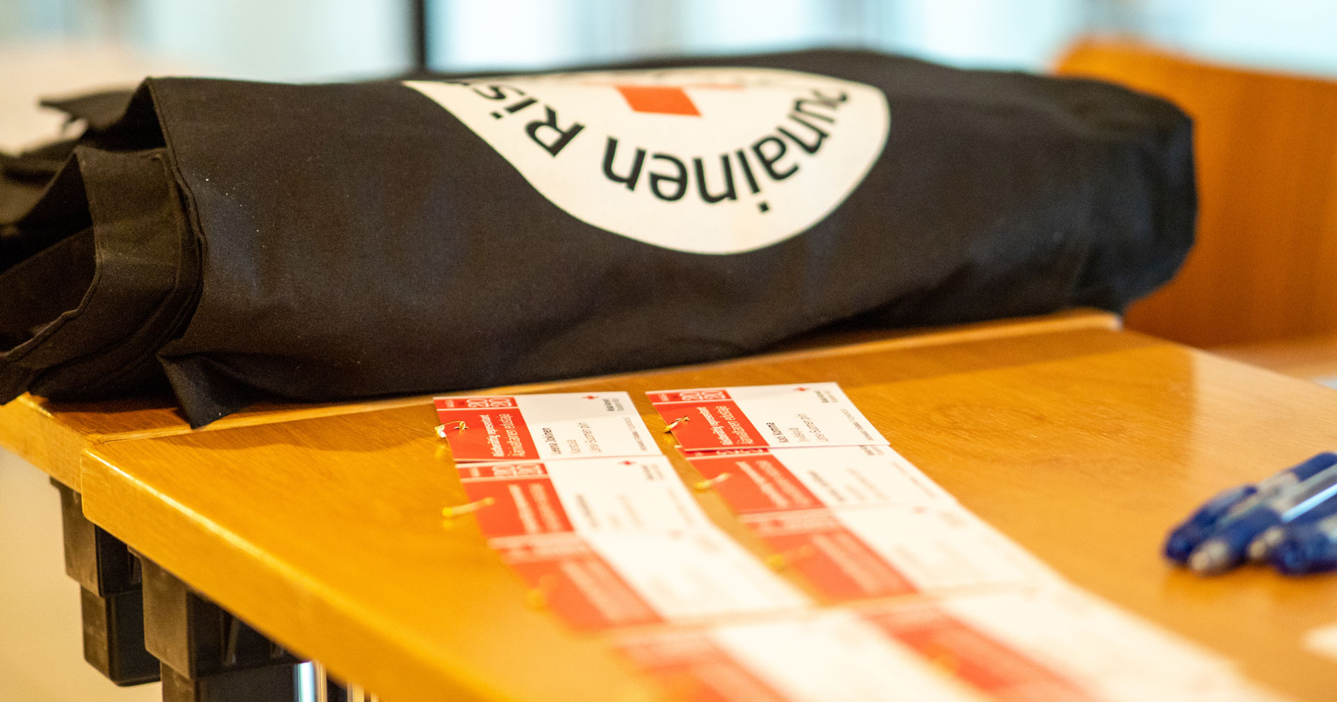 Pöydällä punaisen ristin kassi ja nimilappuja.