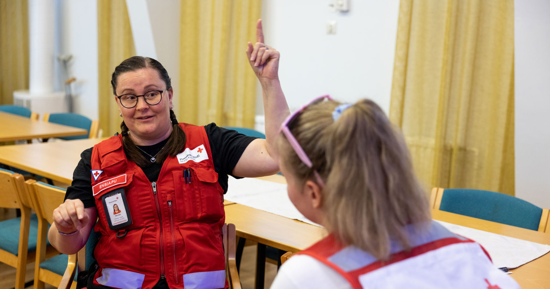 Punaisen Ristin kaksi vapaaehtoista keskustelee johtamisvalmennuksessa. Toinen osoittaa kädellään ylöspäin.