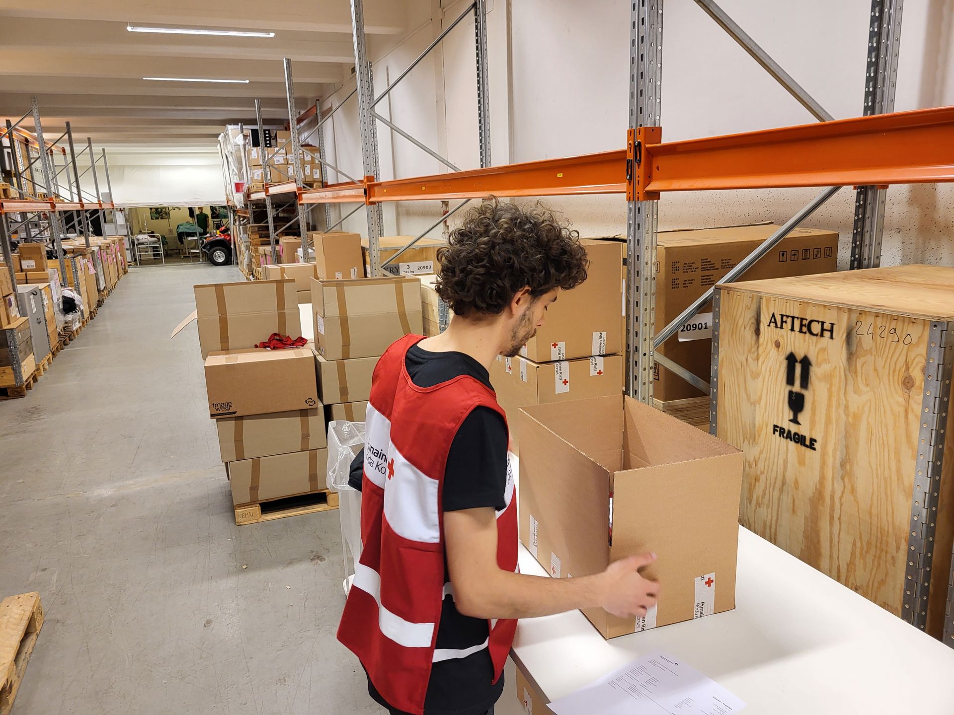 Vapaaehtoinen selkä kameraan päin päällään vapaaehtoisliivi, jossa lukee Punainen Risti.