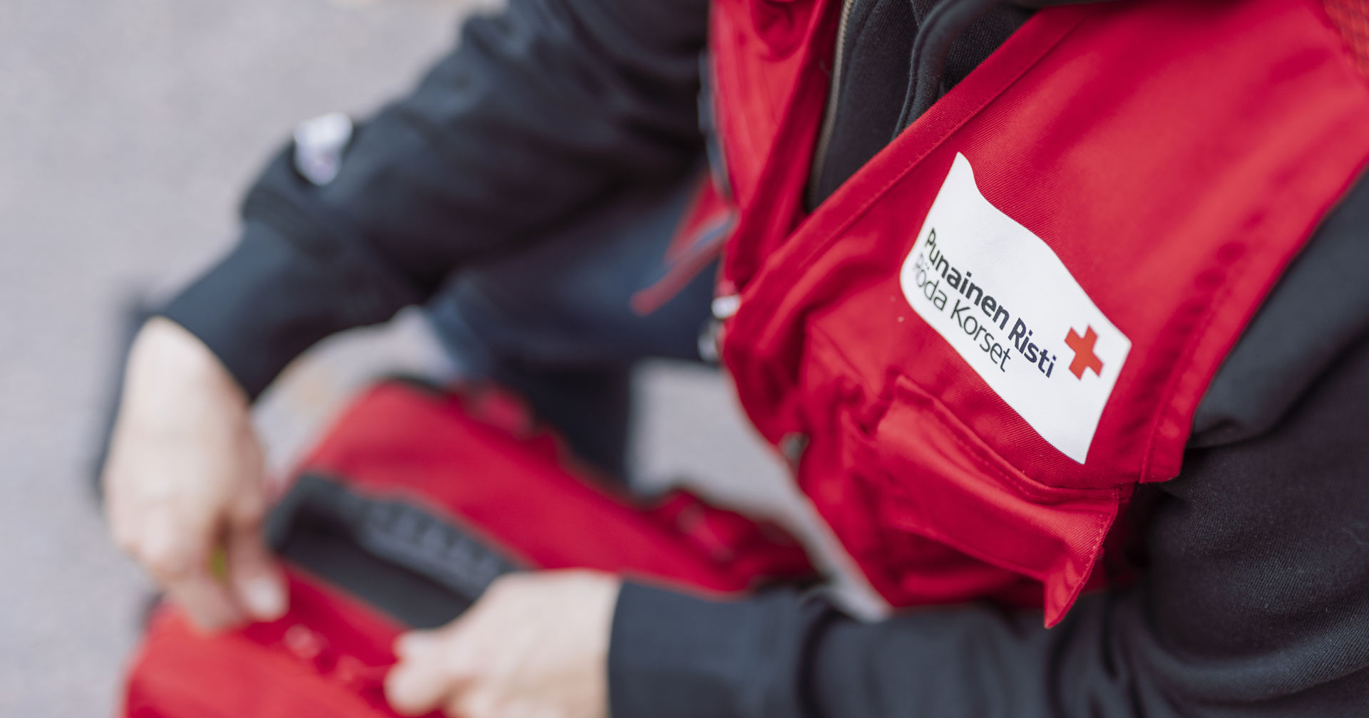 Vapaaehtoinen Punaisen Ristin liivi päällä sulkemassa ensiapulaukkua.