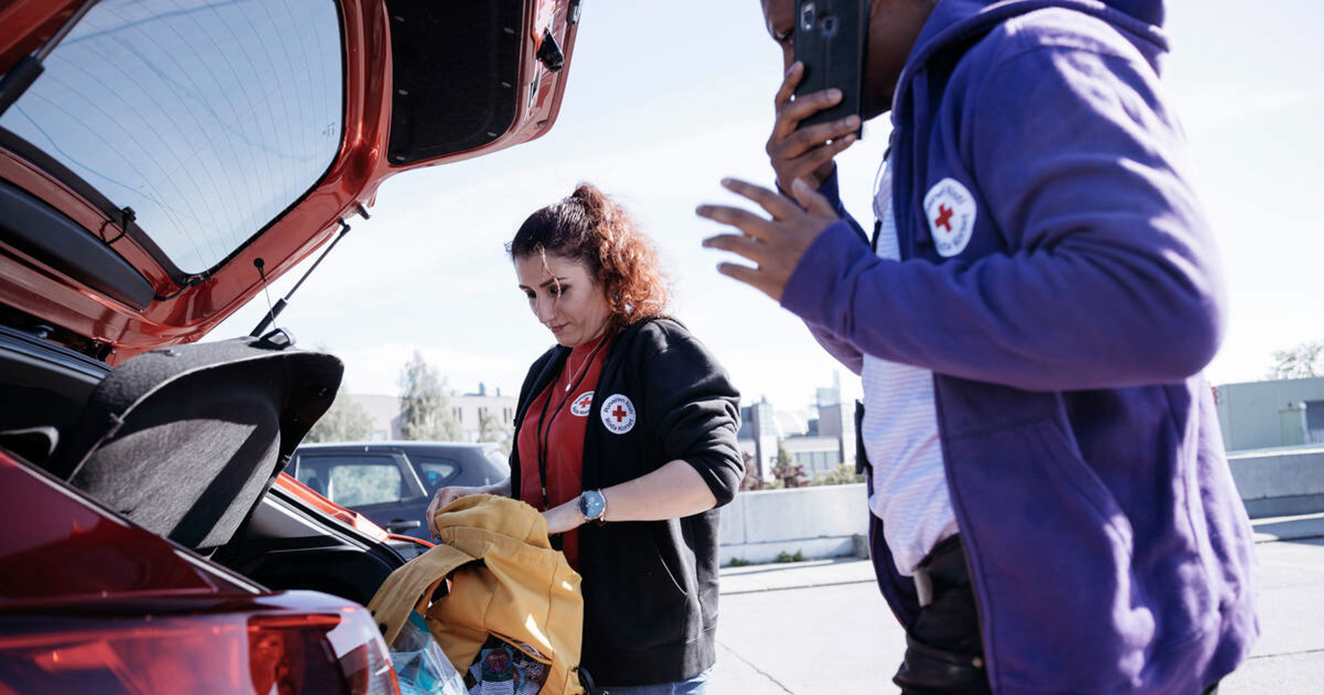 Kaksi Punaisen Ristin vapaaehtoista pakkaa autoa.