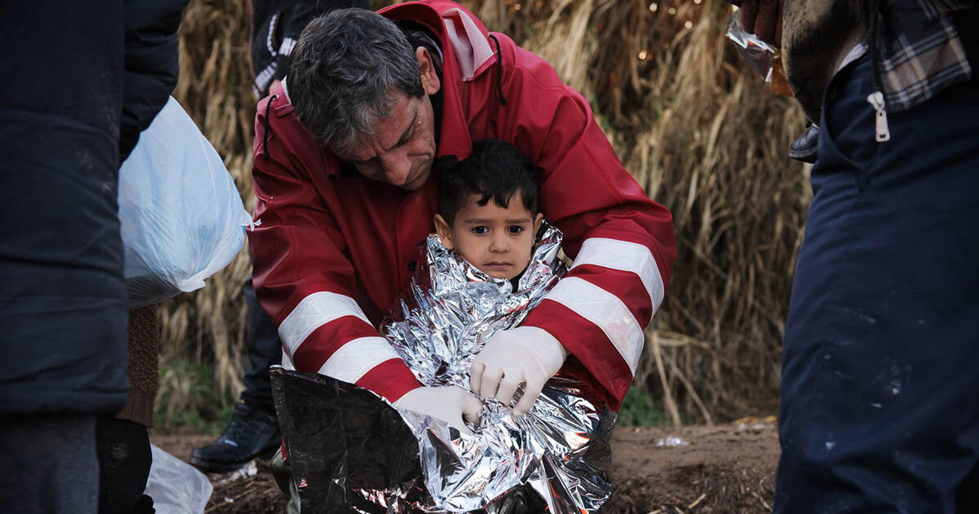Punaisen Ristin työntekijä kietoo foliopeitettä lapsen ympärille.