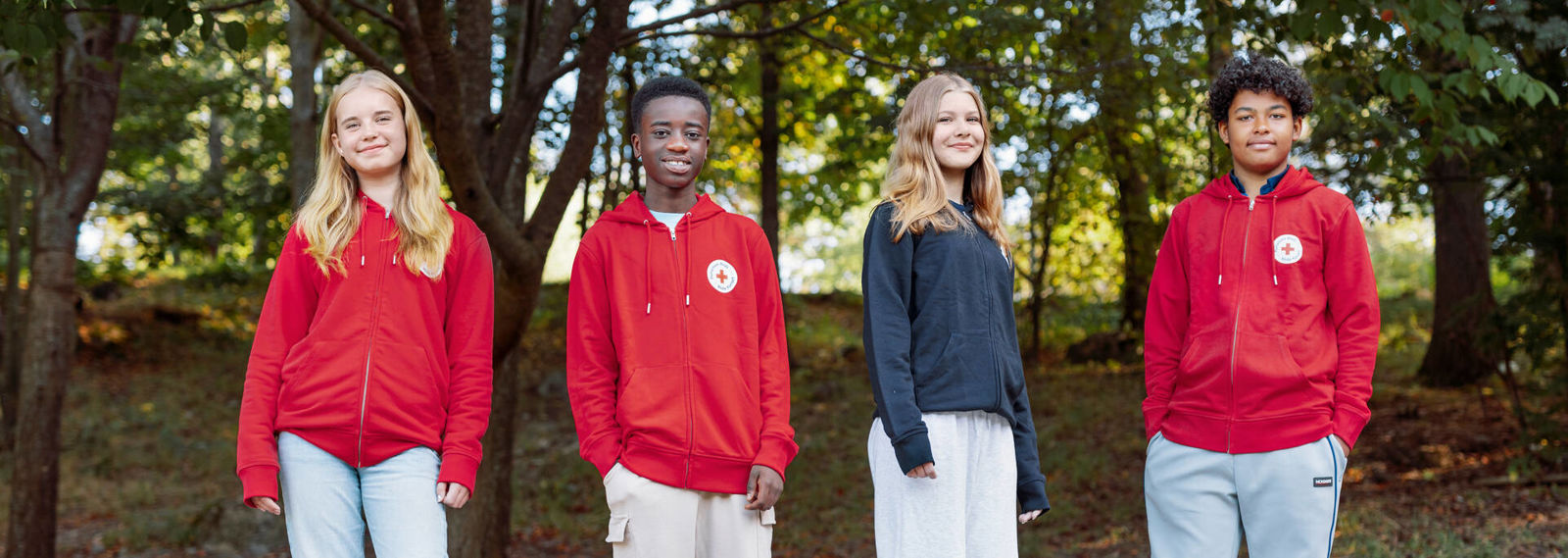 Neljä Punaisen Ristin nuorta vapaaehtoista seivovat ulkona. Heistä kolmella on päällä Punainen Ristin punainen huppari.