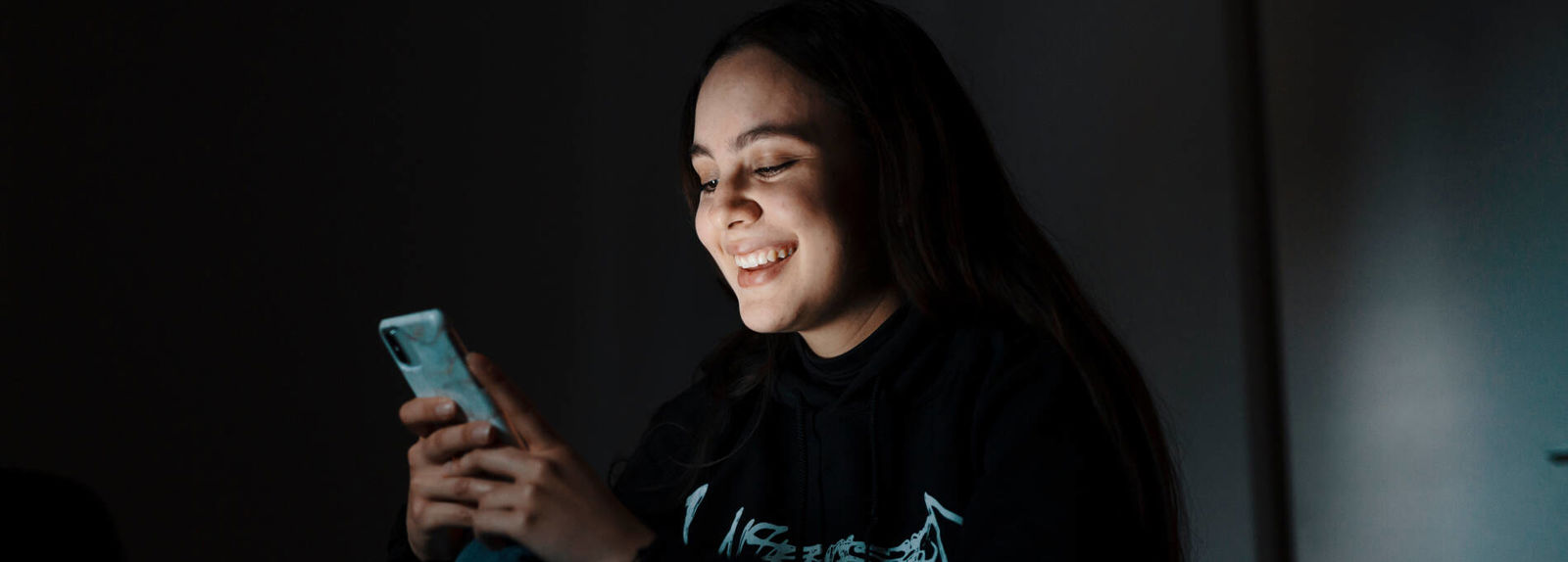 Nuori katsoo puhelinta ja hymyilee.