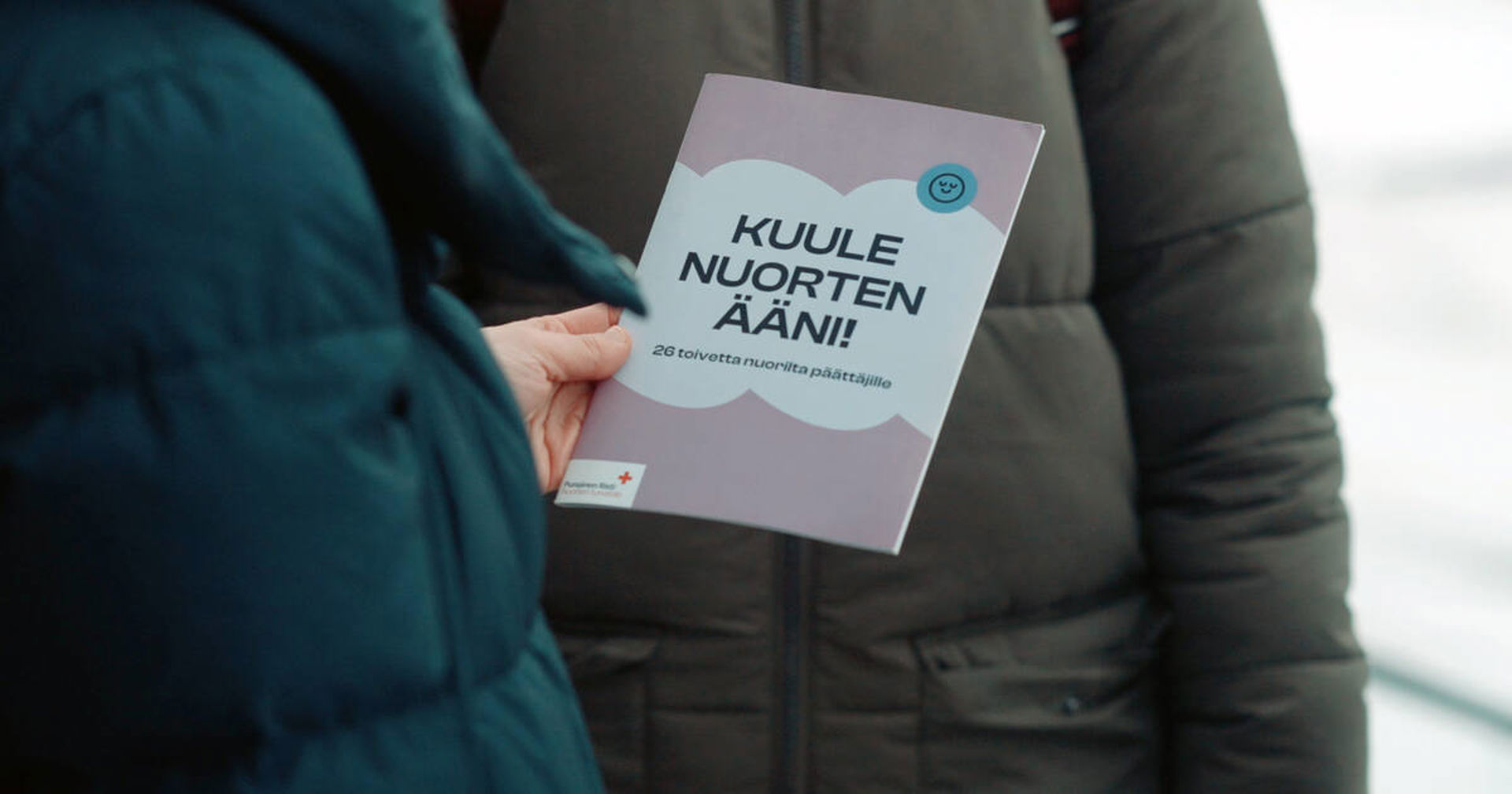 Kuvassa on kaksi henkilöä, joista toiden kädessä on Kuule nuorten ääni! niminen julkaisu.