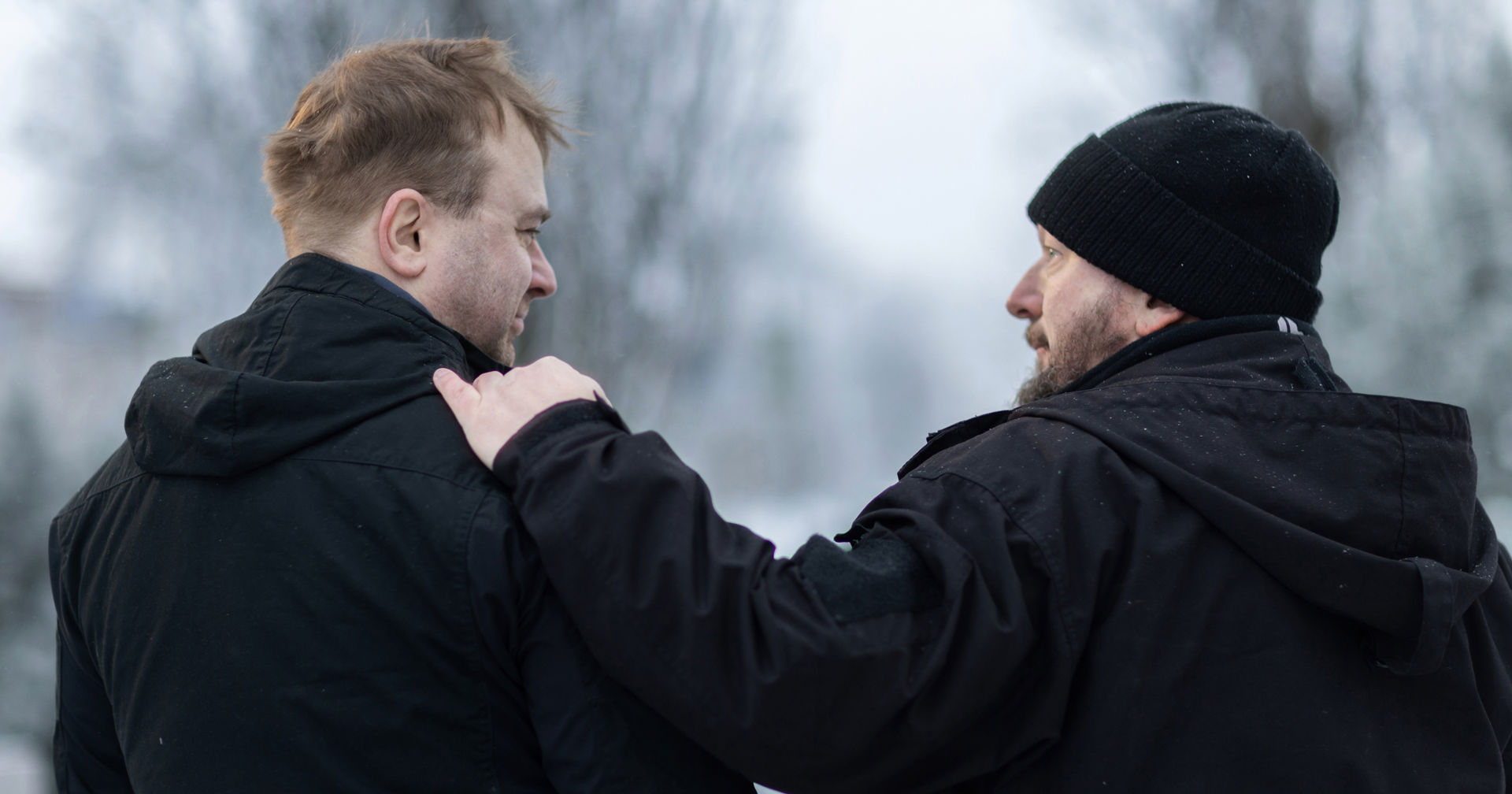 Kaksi henkilöä katsoo toisiaan. Yhdellä on käsi toisen olalla.