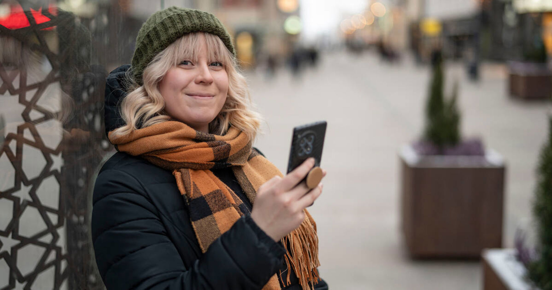Henkilö hymyilee puhelin kädessään.