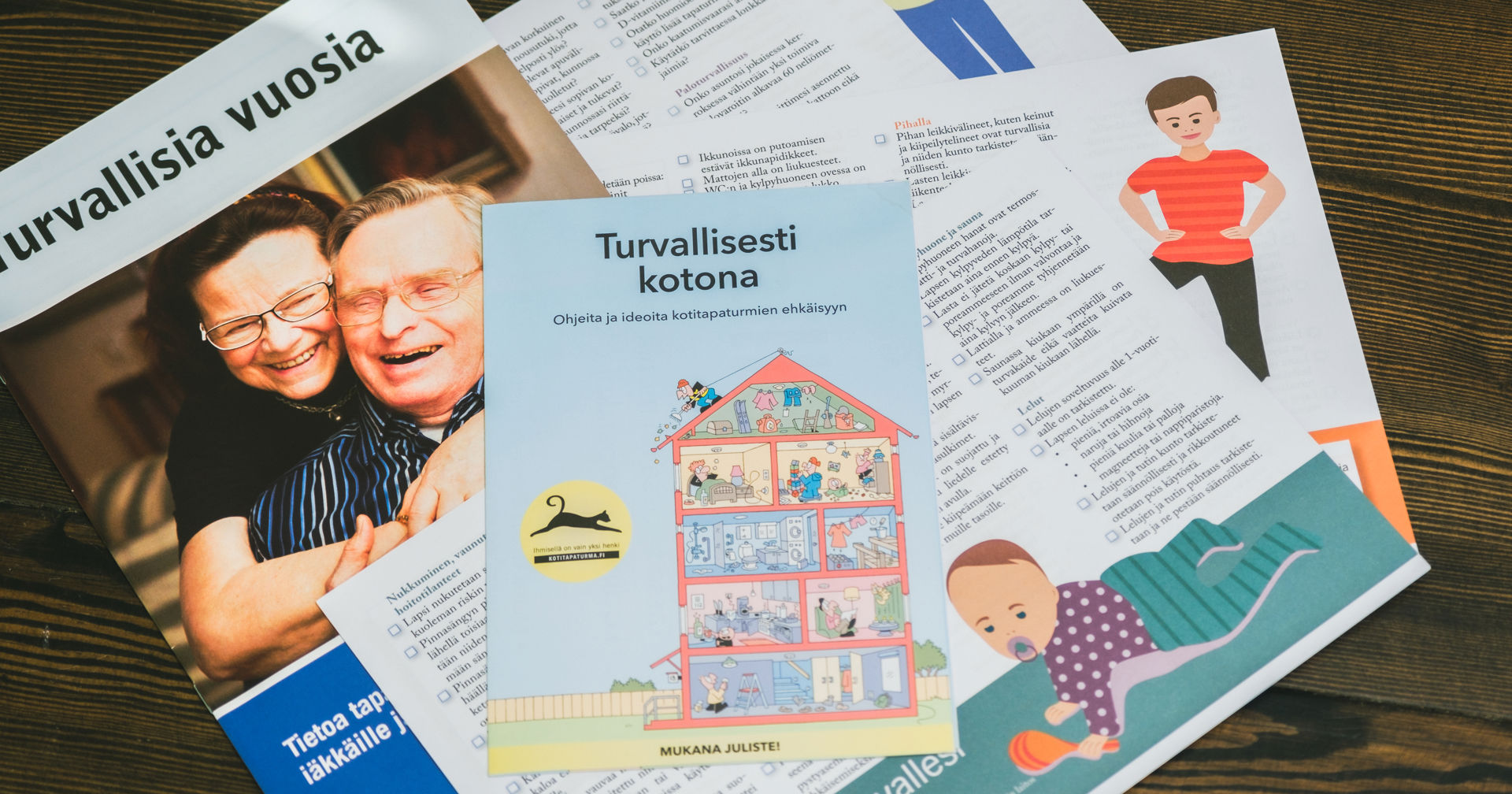 Turvallisuusesitteitä pöydällä. Yhdessä lukee: "turvallisia vuosia", ja toisessa, "turvallisesti kotona."