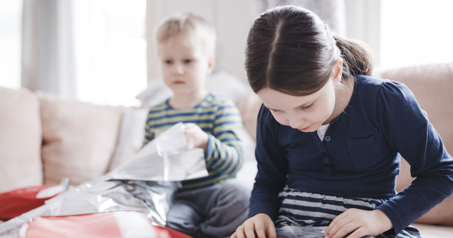 Kaksi lasta istuu sohvalla ja tutkii ensiapulaukun tavaroita.