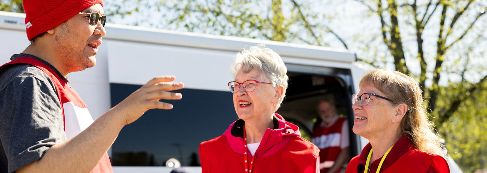 Nuori neuvoo sohvalla istuvaa henkilöä ja osoittaa tämän kädessä olevaa tablettia.
