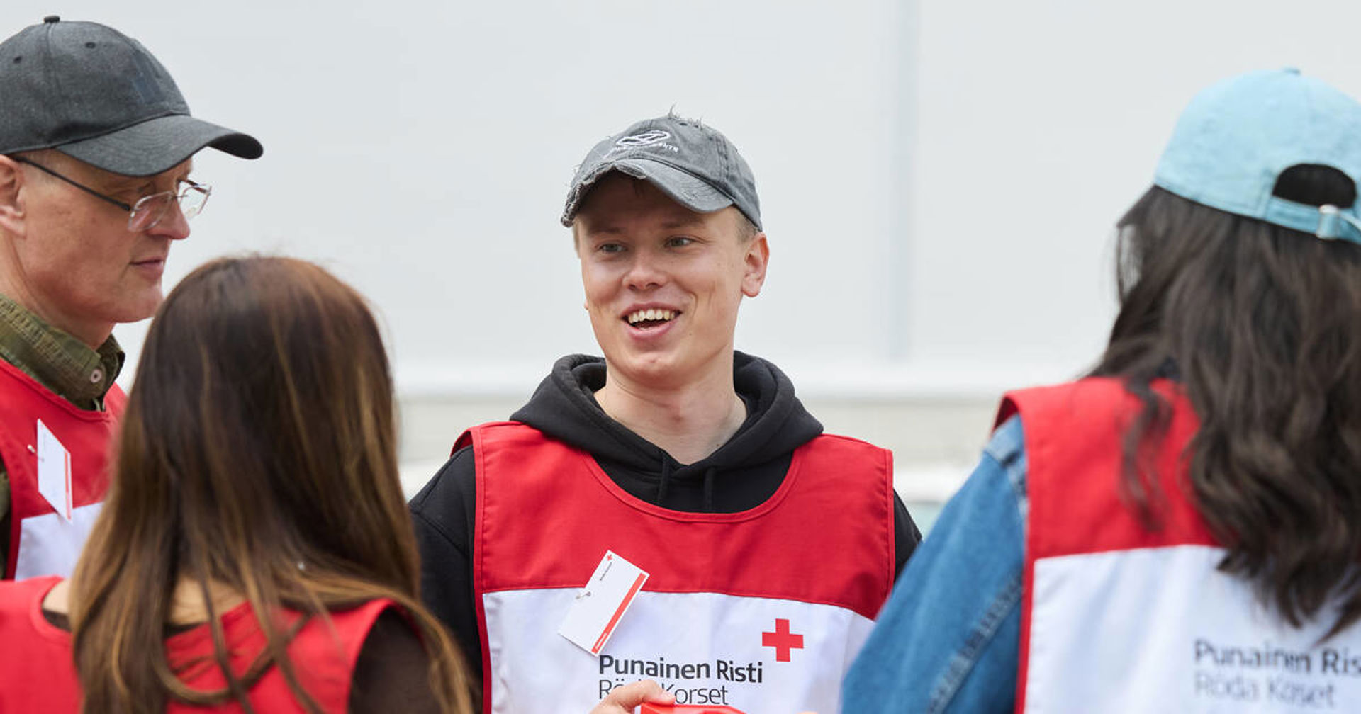 Neljän henkilön porukka juttelee ulkona keräysliivit yllään.