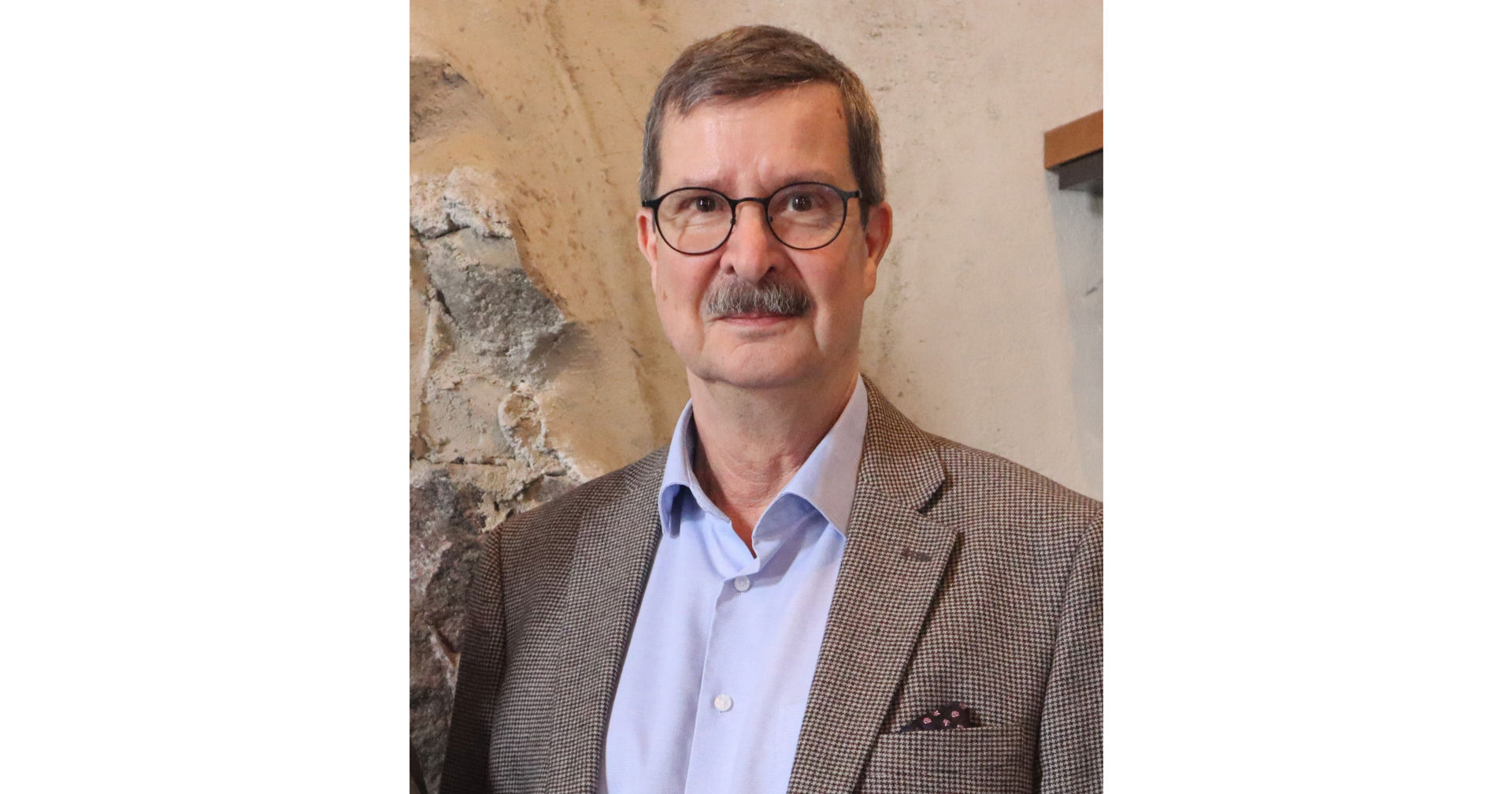 Kenneth Nygård katsoo kohti kameraa, päällään vaalea kauluspaita ja ruskeasävyinen pikkutakki.