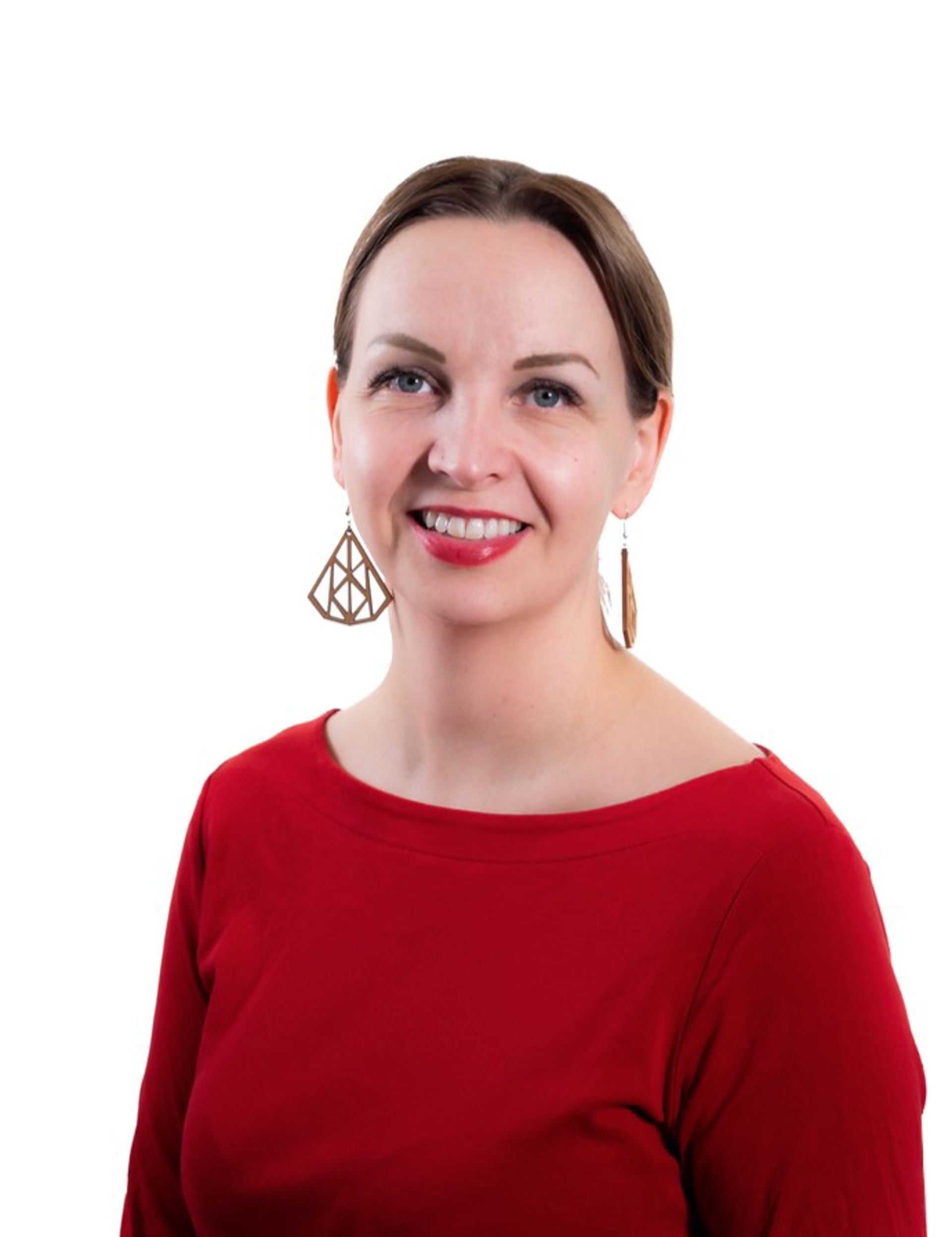 Maarit Villman katsoo kohti kameraa, päällään punainen pusero ja isot korvakorut.