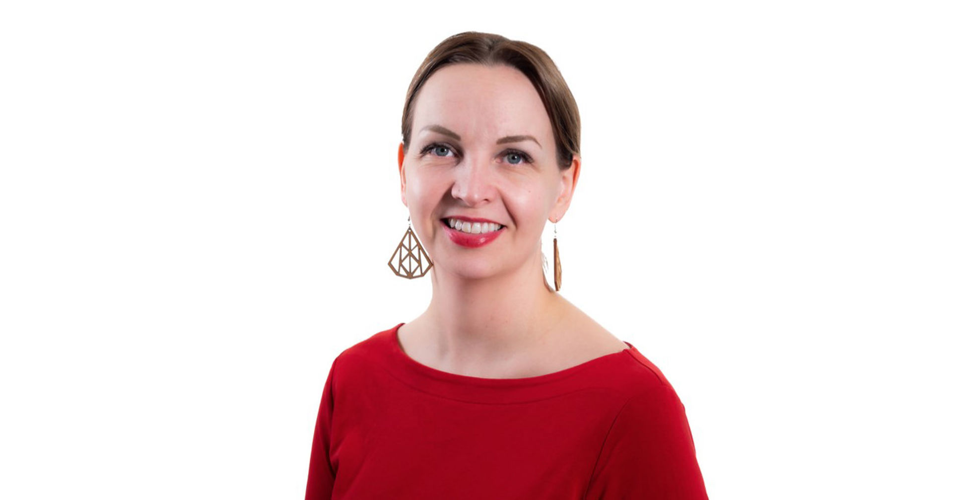 Maarit Villman katsoo kohti kameraa, päällään punainen pusero ja isot korvakorut.