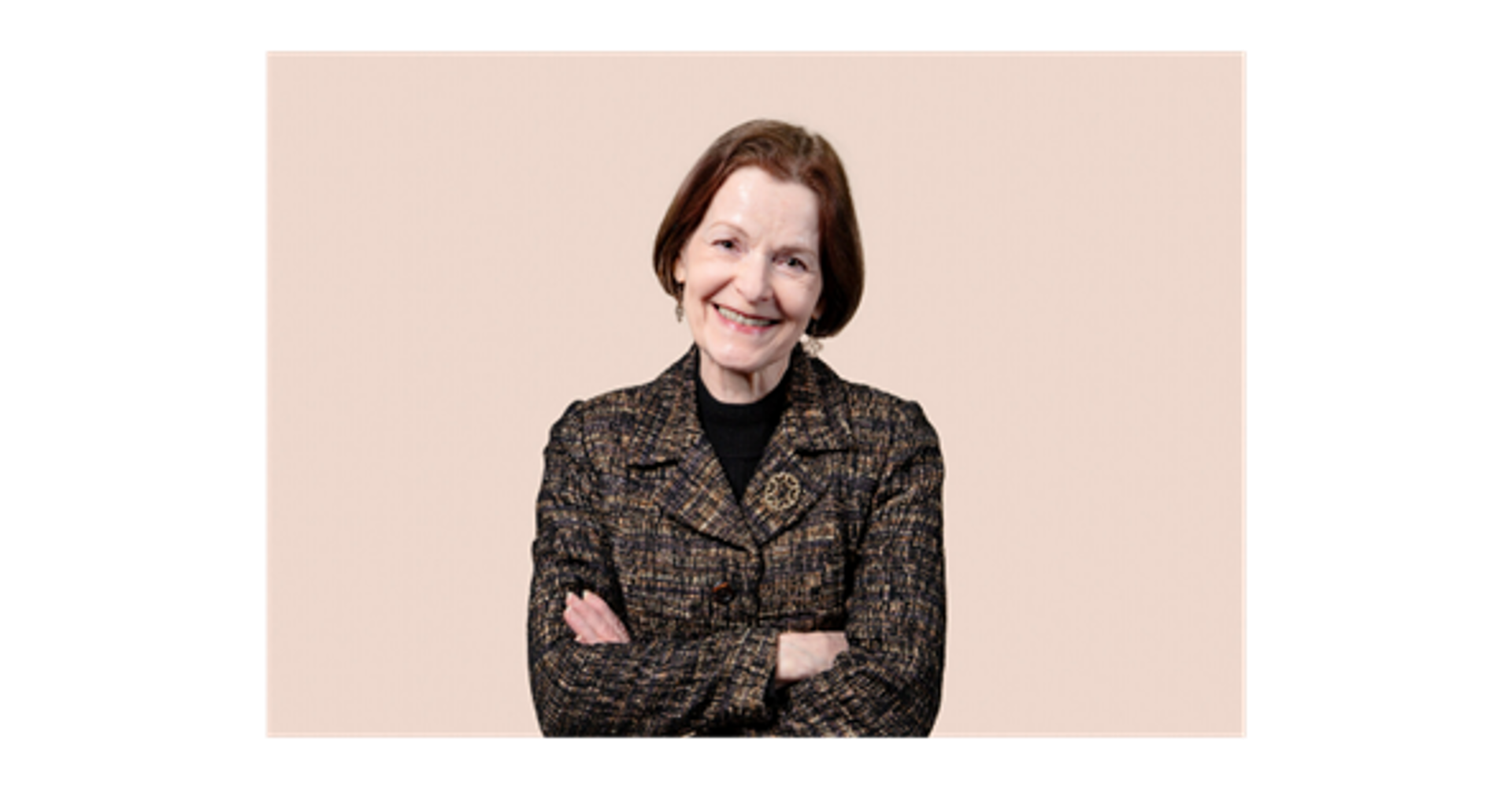Marja Lehto seisoo vaaleaa taustaa vasten kädet ristissä, päällään kuviollinen jakku ja tumma poolopaita.