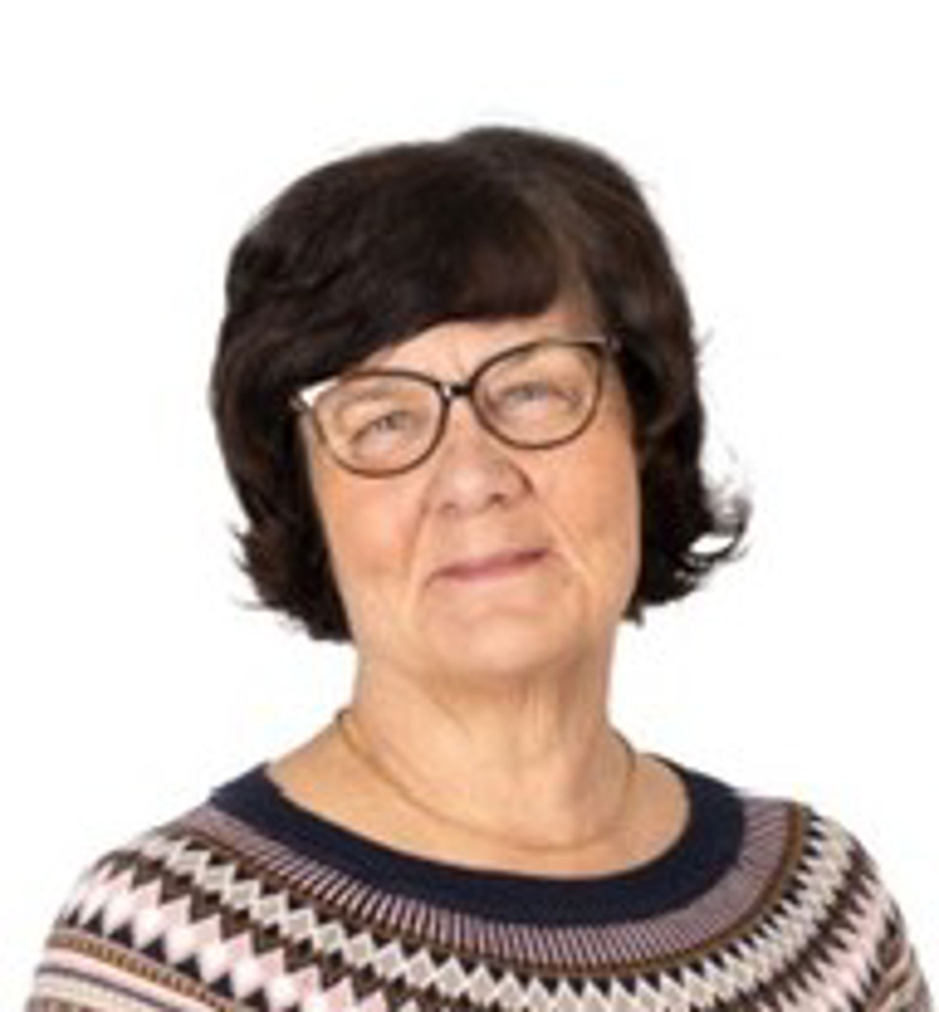 Marju Sjösten katsoo kohti kameraa, päällään kuviollinen neule ja silmälasit.