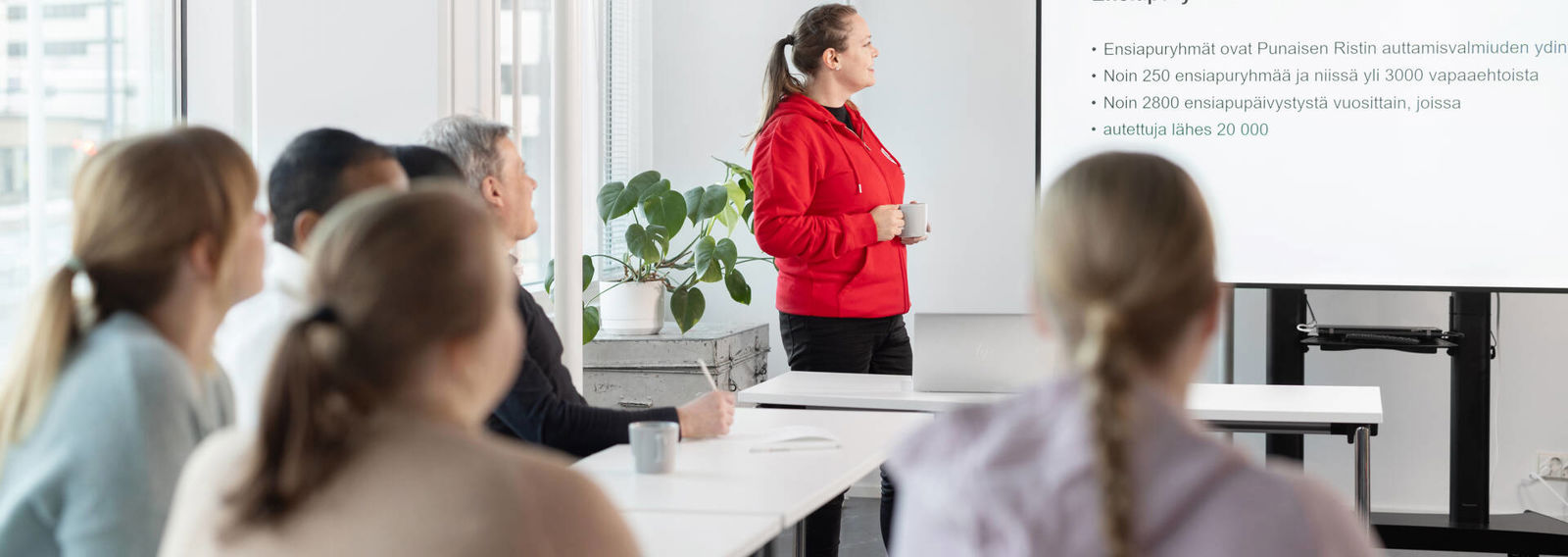 Vapaaehtoiset seuraavat kouluttajan vetämää esitystä