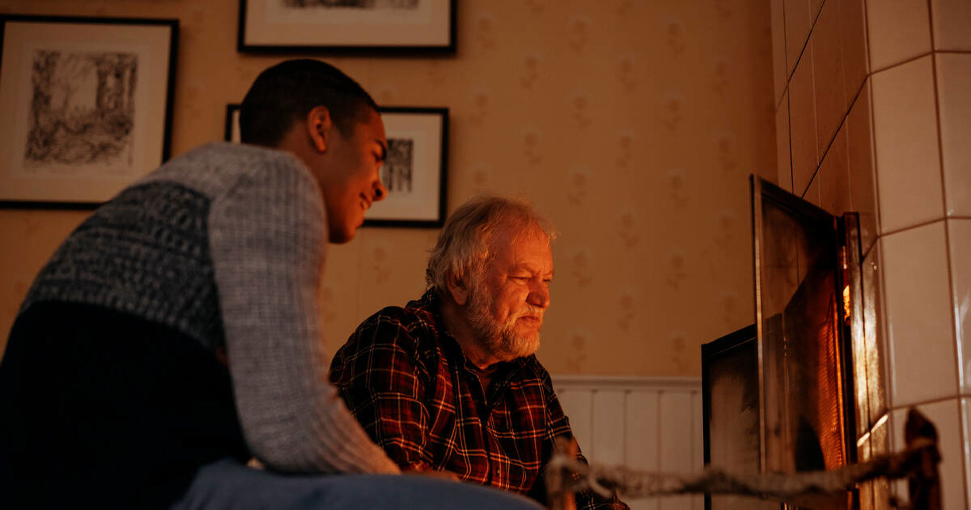 Två personer tittar ut mot eldstaden, ler och pratar.