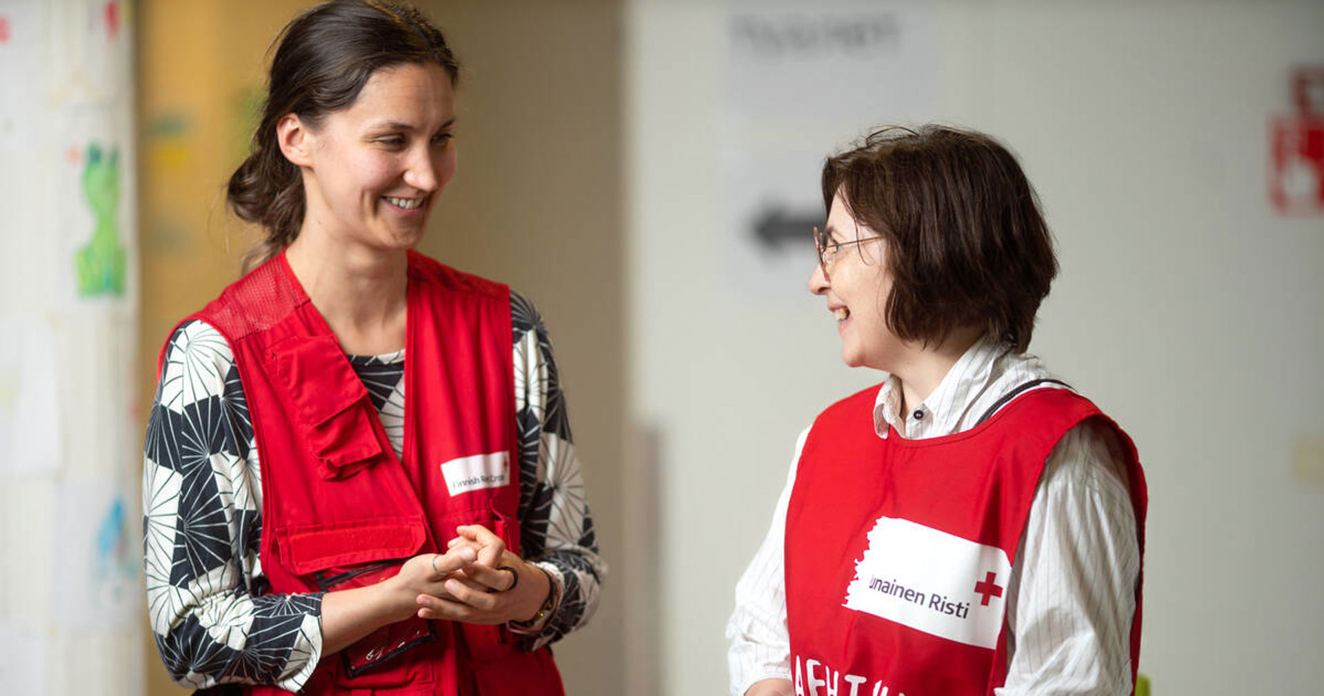 Kaksi Punaisen Ristin vapaaehtoista katsoo hymyillen toisiaan.