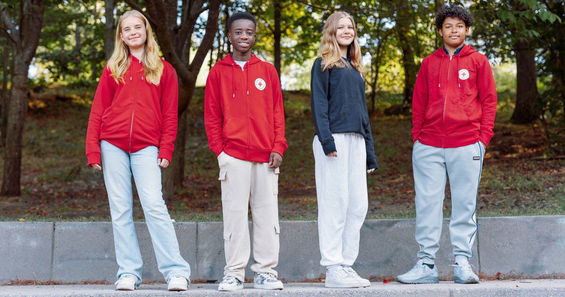 Neljä nuorta katsoo kameraan Punaisen Ristin hupparit päällään.