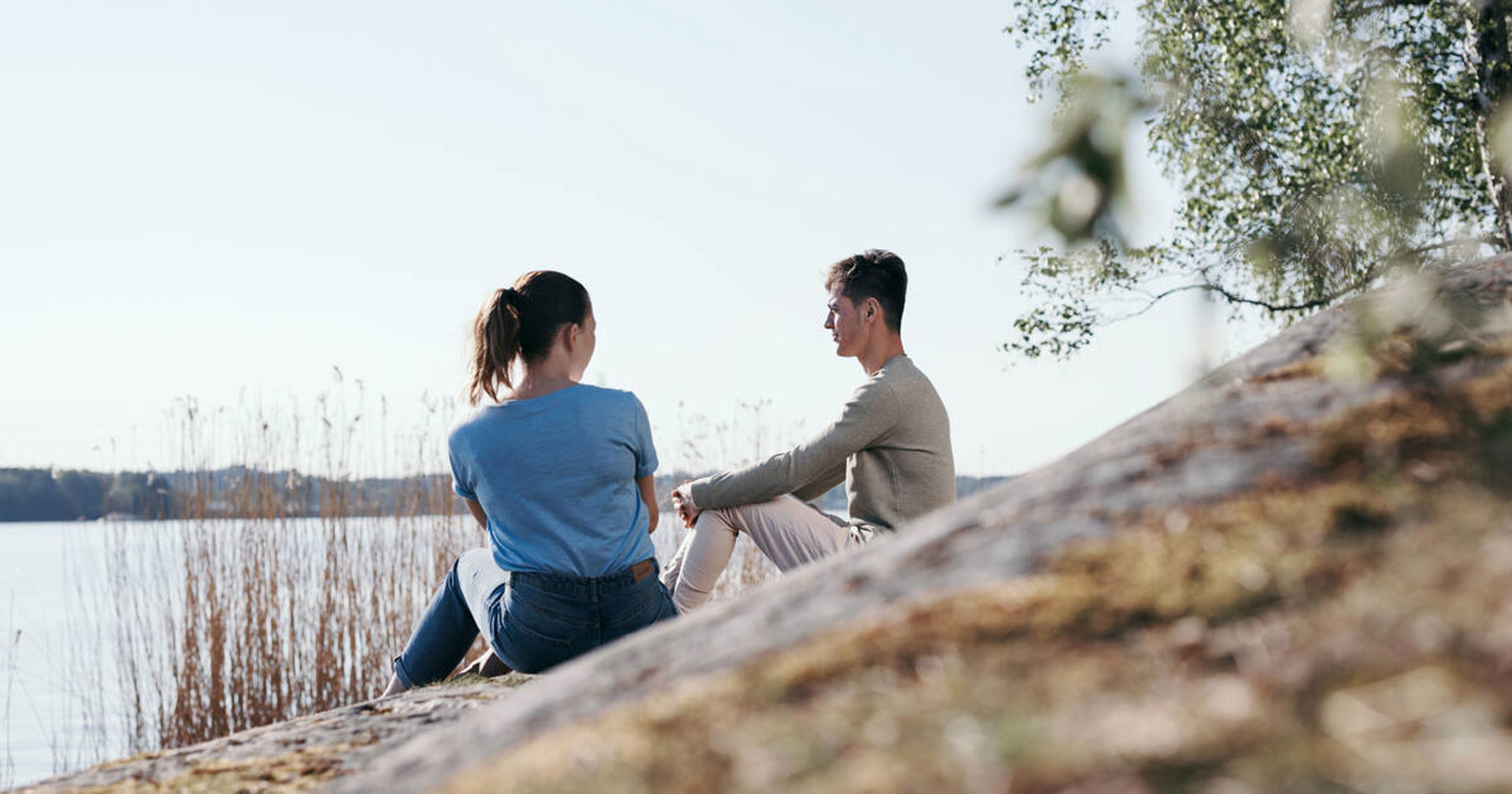 Kaksi henkilöä juttelee rantakallioilla.