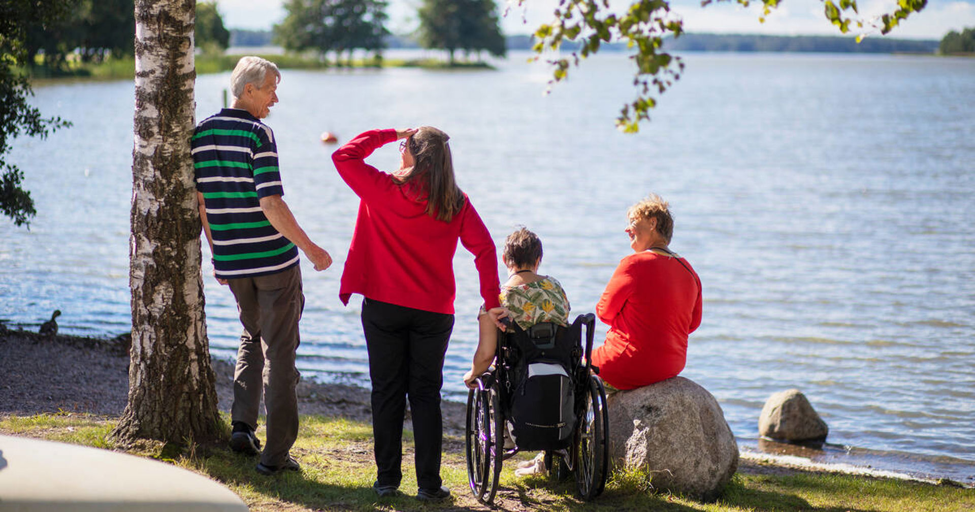 Neljä henkilöä järven rannalla.